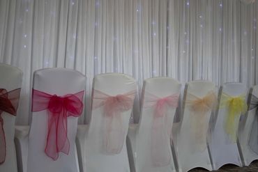 Row of chair sashes in multiple colours in front of the starlight backdrop. 