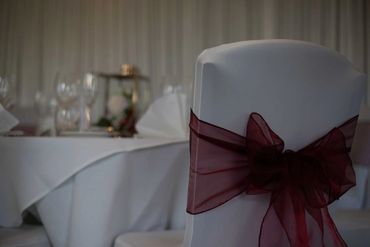 Close up of burgundy sash. Starlight backdrop and dressed table in background.
