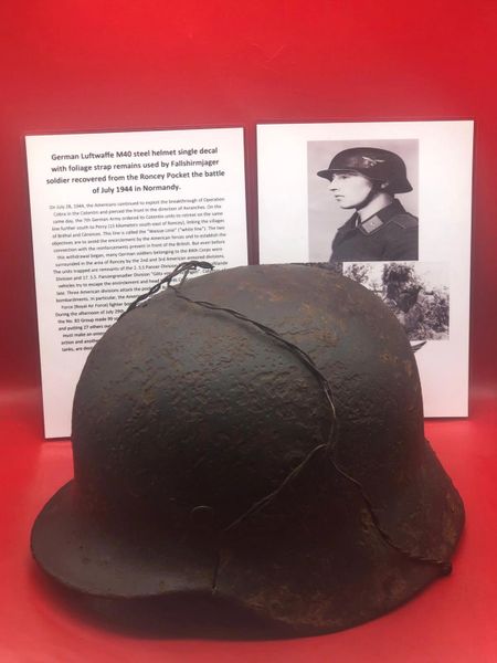 German Luftwaffe M40 steel helmet with blue paint remains, single decal and foliage strap,battle damaged used by Fallshirmjager soldier recovered from the Roncey Pocket the battle in July 1944 in Normandy.
