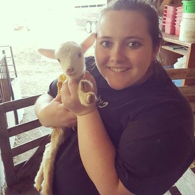 Maryellen on her home farm in Alberta Canada holding a baby lamb