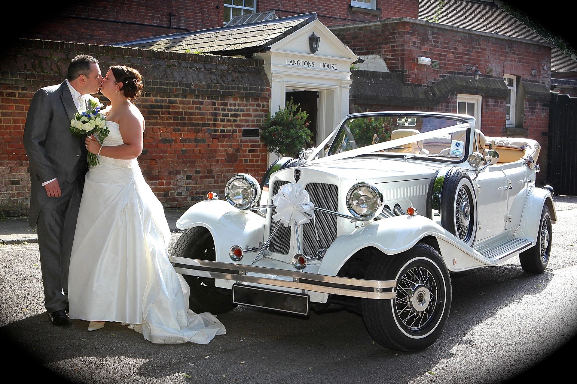 bride + groom kissing next to Beauford wedding car