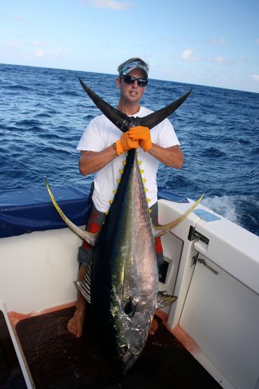 regular tahiti sport fishing guest holds up his personal best yellow fin tuna