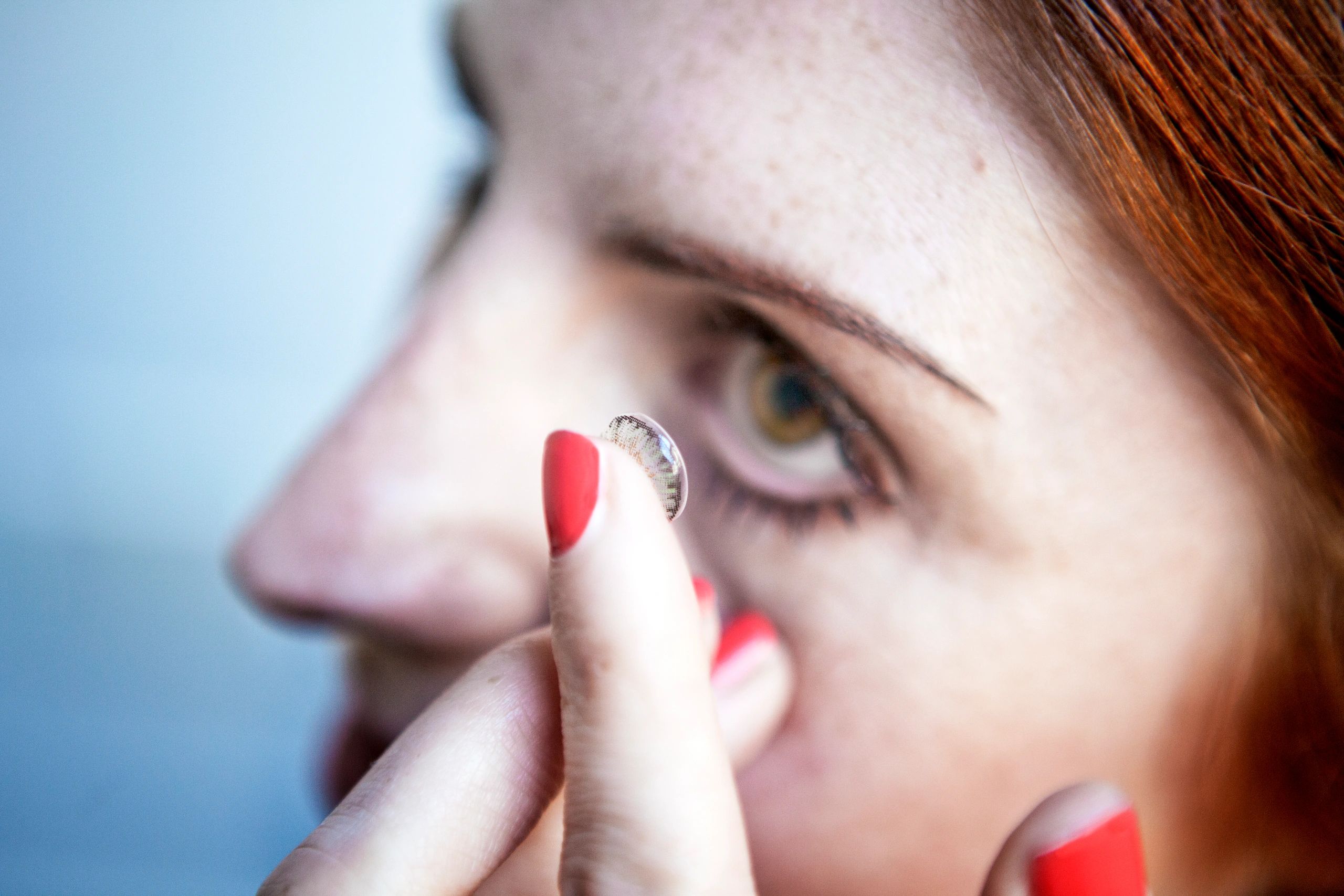 woman placing a contact lens on her eye