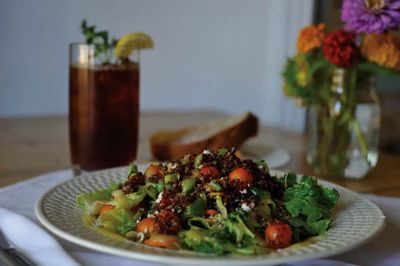Fresh salad with cherry tomatoes and a drink on a wooden table.