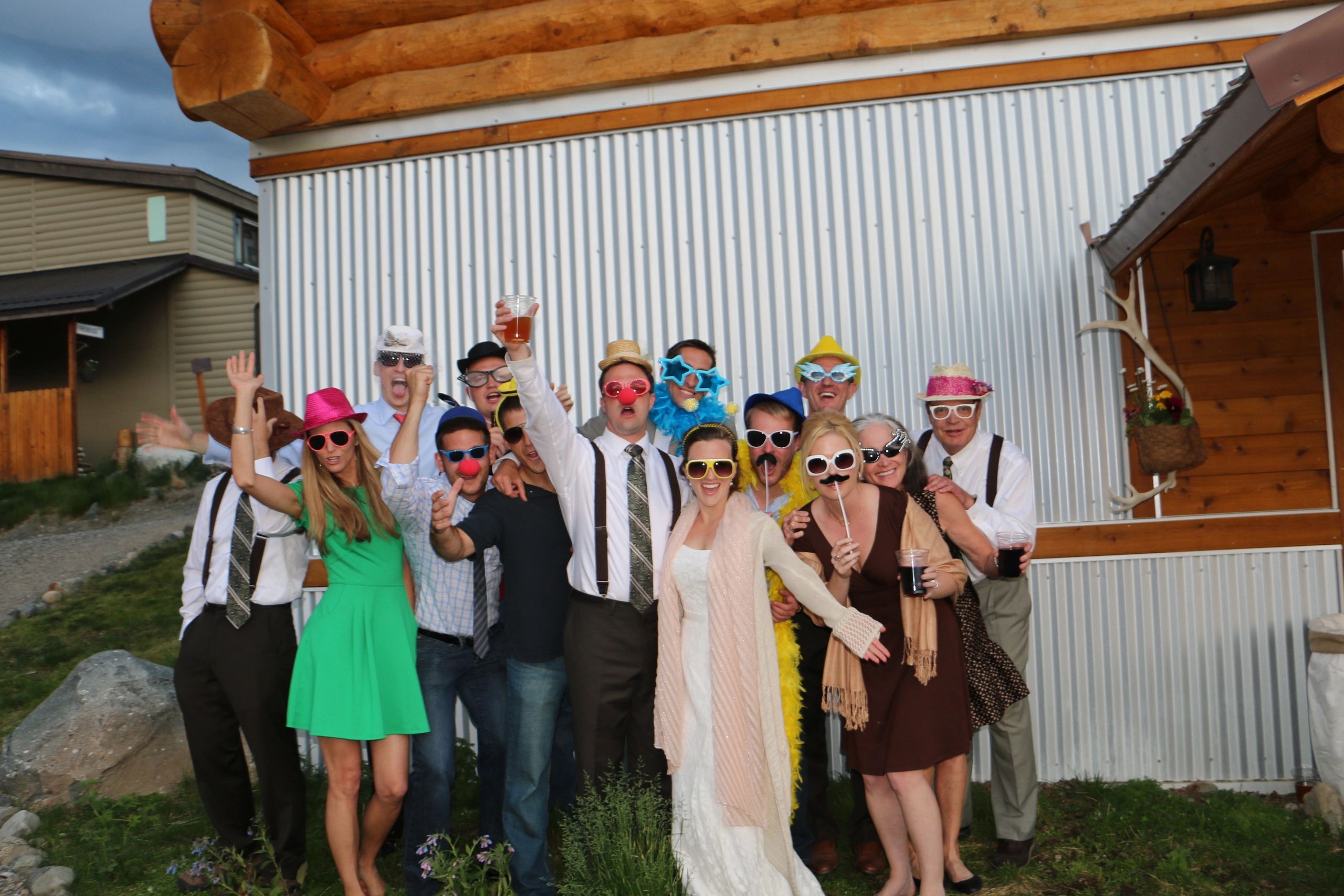 Large group of people at wedding reception, smiling with photobooth props 