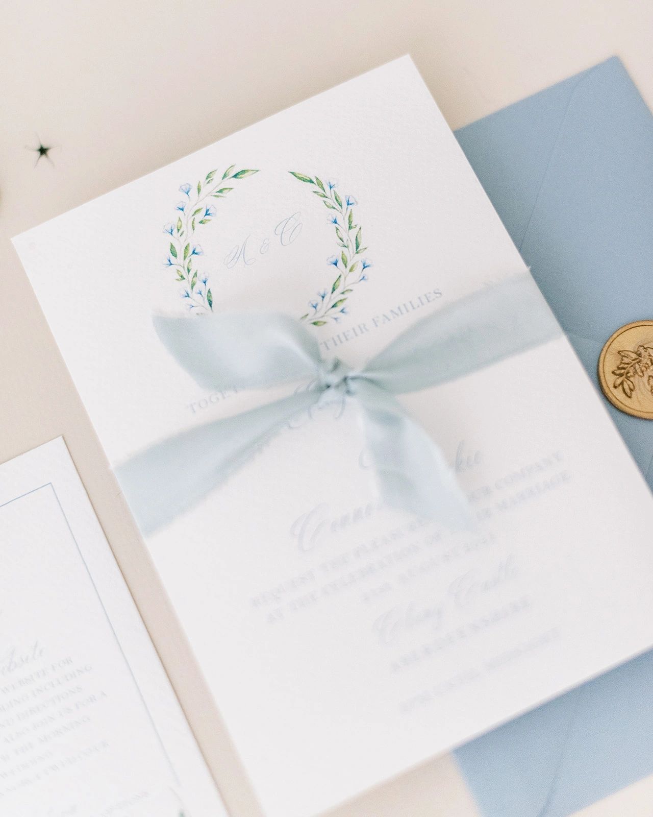 Blue floral watercolour invitation tied with blue ribbon and a gold wax seal