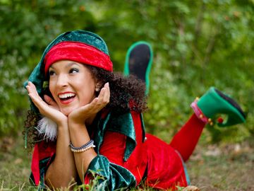 Lutin de Noël souriante en costume rouge et vert, animation festive pour enfants