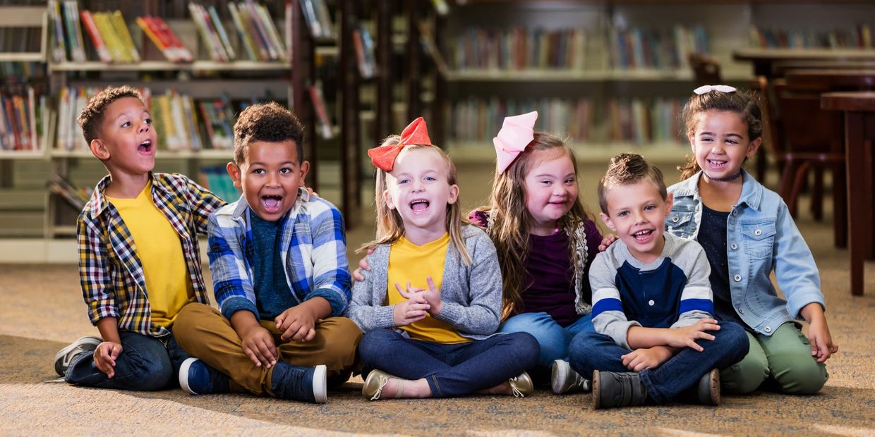 6 exceptional students at elementary school sit on floor of library awaiting speech therapy services