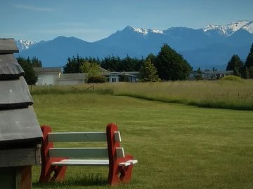 Red and white bench facing a backdrop of  the Olympic Mountains