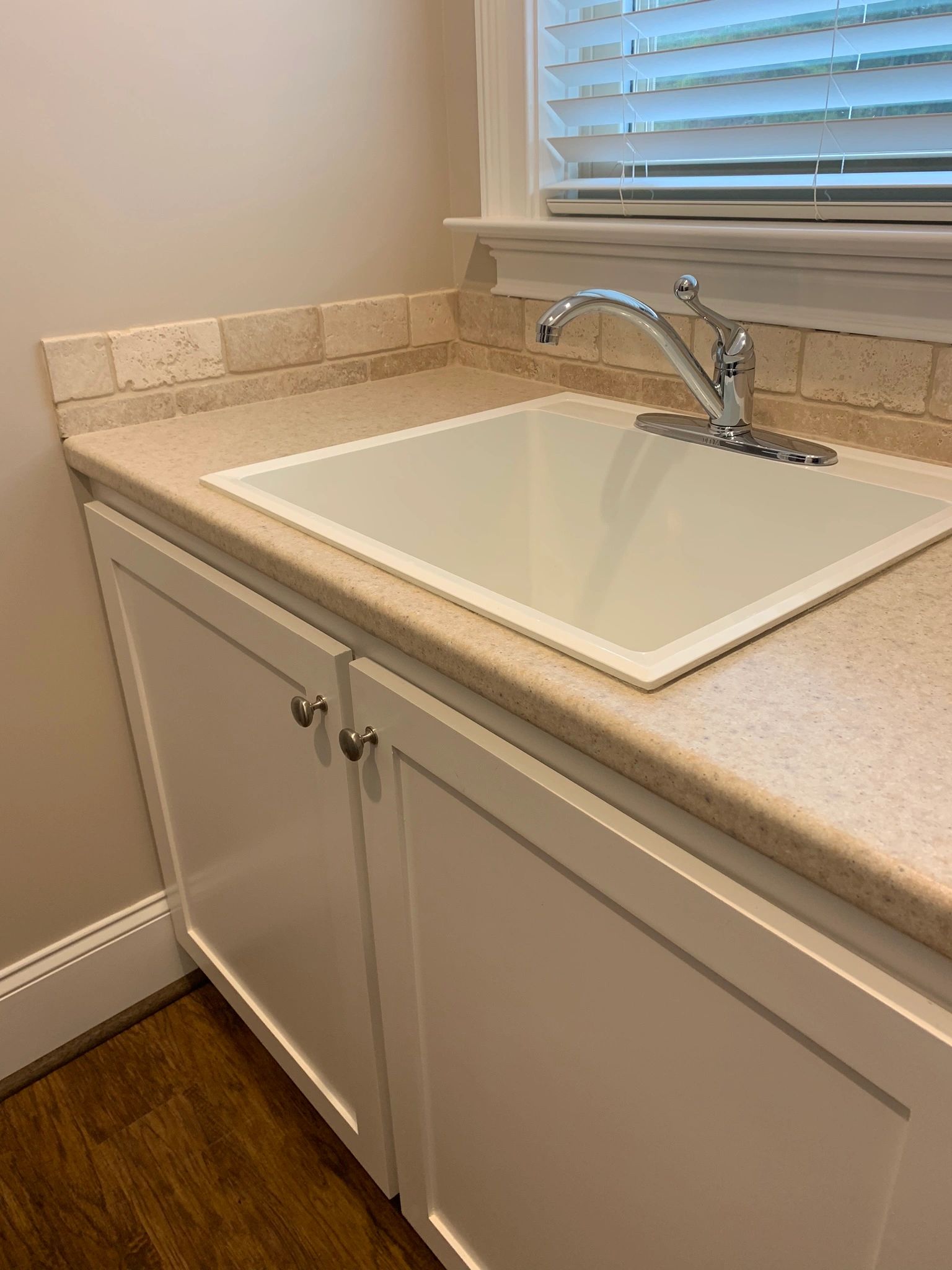 Custom cabinetry for laundry sink with tile backsplash