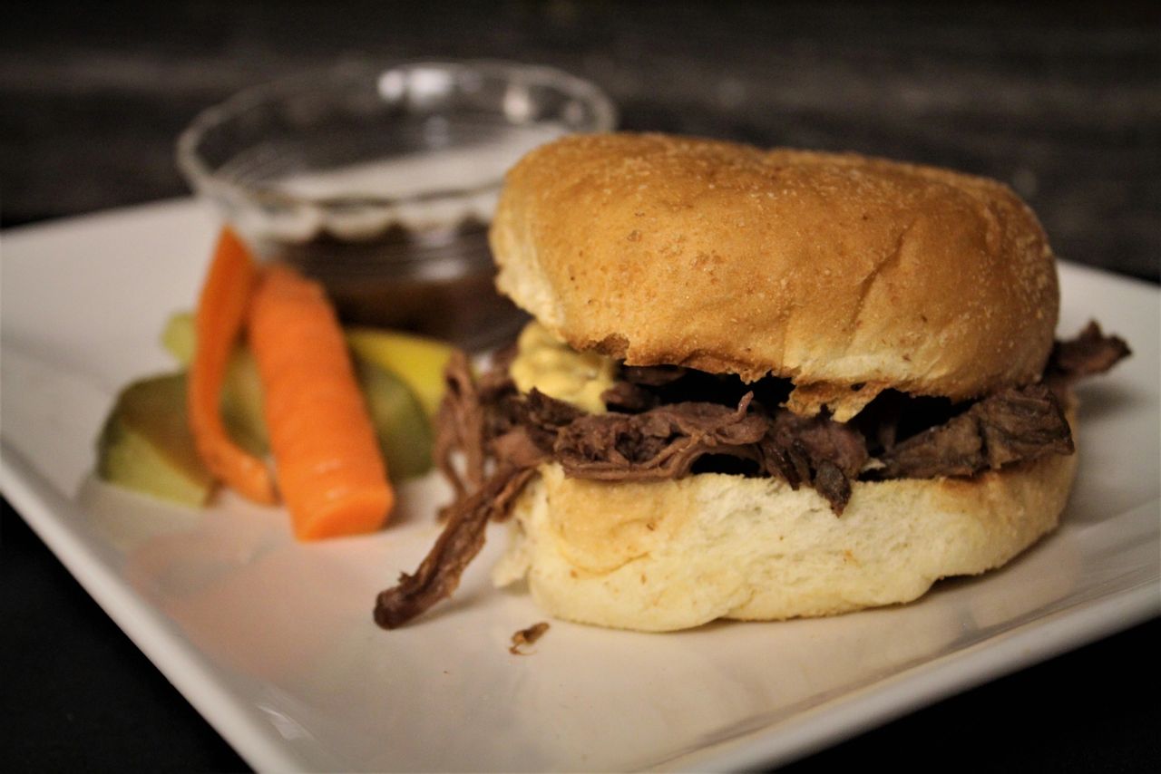 Bison dip sandwich with a side of jus and vegetables