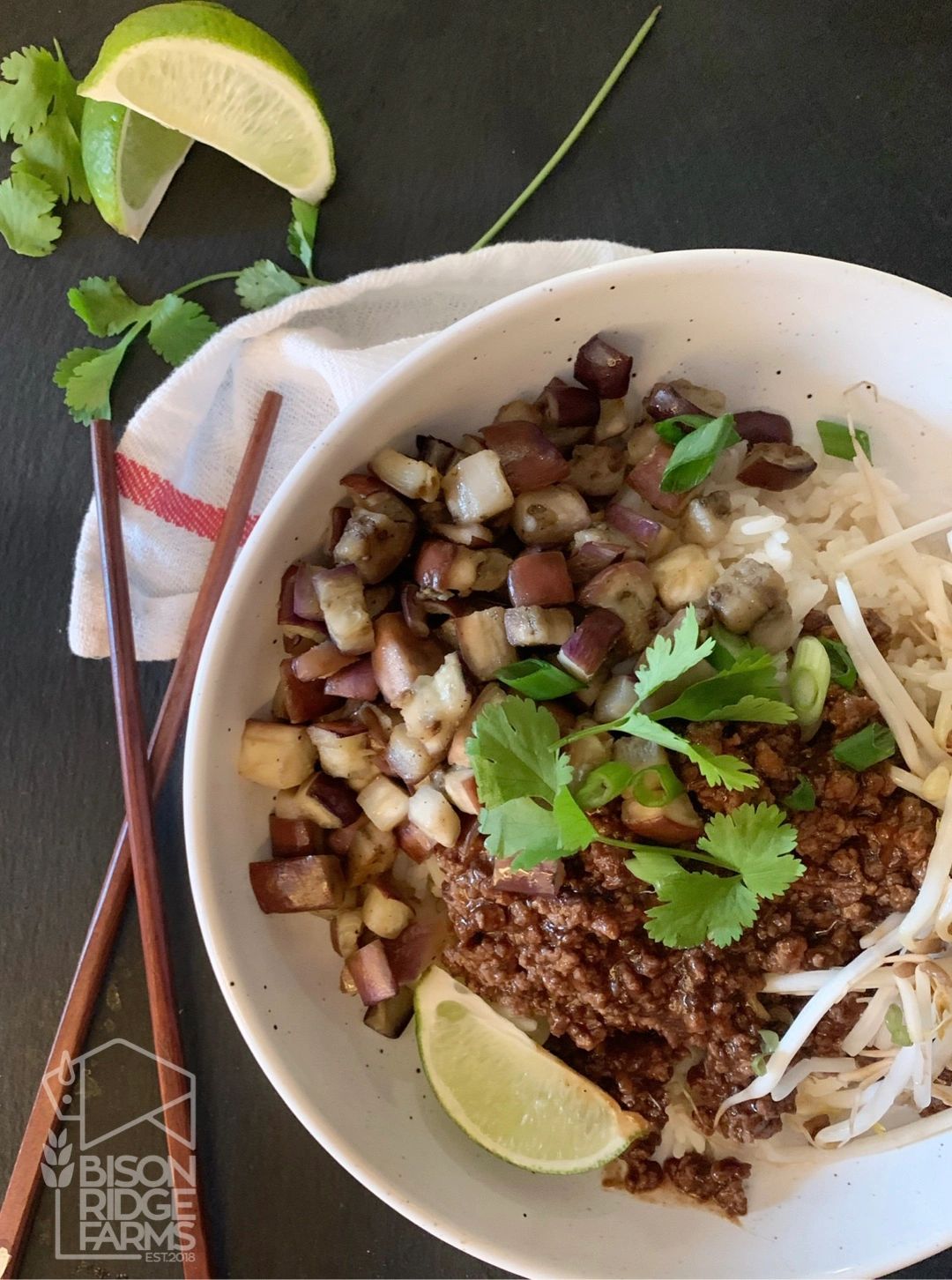 Bison and eggplant rice bowl garnished with lime and parsley