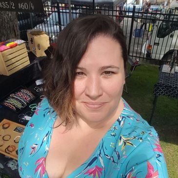 Short dark haired woman smiling, wearing a floral blue shirt 