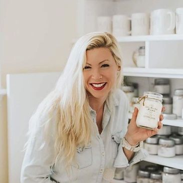 Woman artisan posing with handmade soy wax candle in candle store