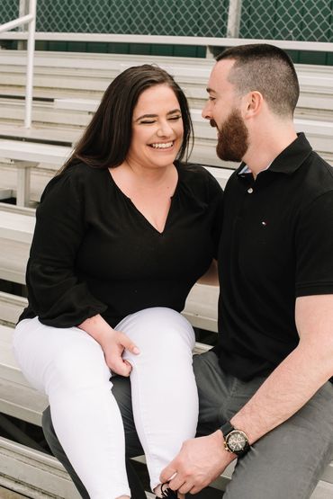 Couple laughing at a memory on stadium stands. 