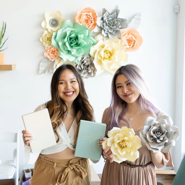 two girls holding lavendaire artist of life workbooks, paper crafted floral decorations at launch