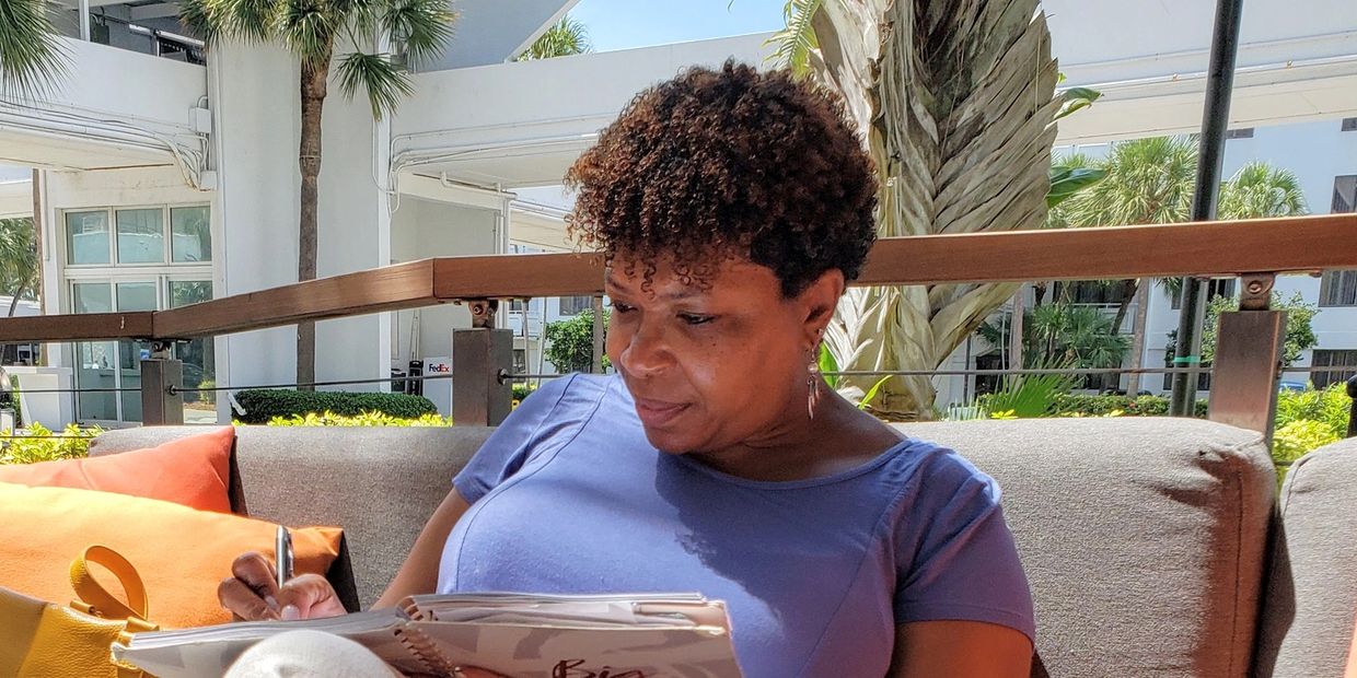 woman sitting on a couch outside writing in a book