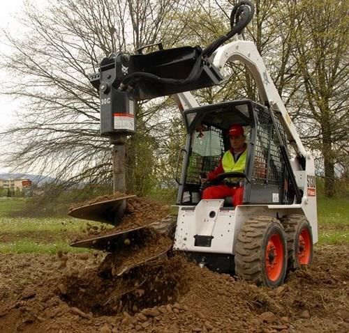 Hydraulic post hole digger store for skid steer