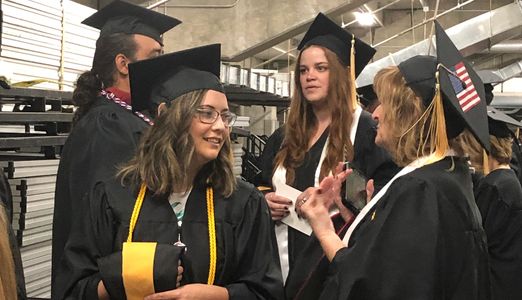 Lus's final class waits to graduate in May 2019.  Wearing silk stoles that read "What Would Lu Do?"