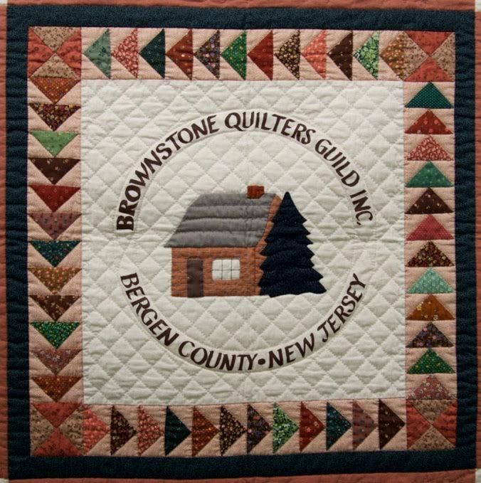 Quilt with Brownstone Quilters Guild logo and colorful border.