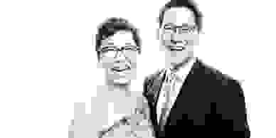 black and white photo of laughing couple wearing glasses and formal attire 