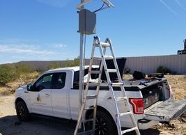 Truck next to an electrical control panel on a pole.