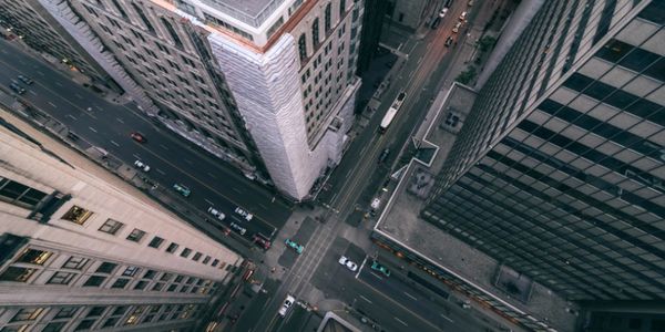 A top-down view of a city intersection with skyscrapers and a bustling street.