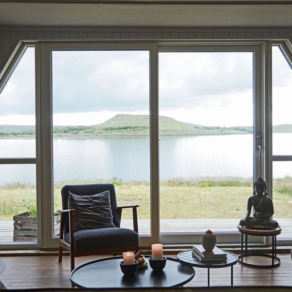 Cozy chair by large window overlooking lake and hill.