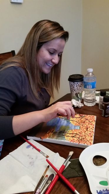 Woman painting a colorful autumn tree scene
