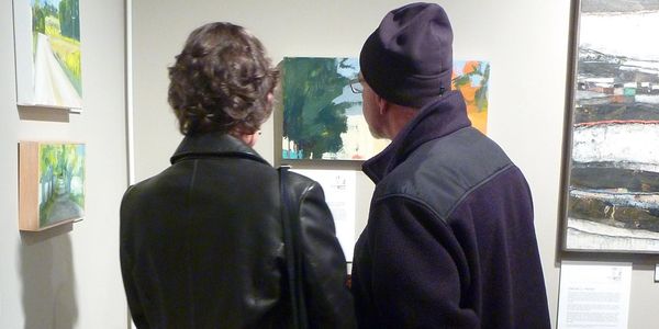 Two people admiring artwork during an art opening reception at Ledbetter Gallery.