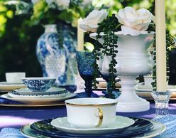 reception table with blue and white vases, florals and table settings.