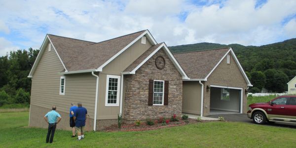 three men checking out a house with red car