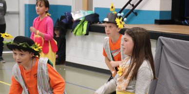 Children dressed in colorful costumes performing indoors.