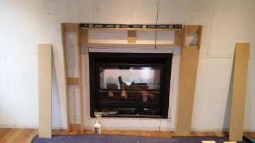 Installation d'une cheminée encastrée en construction.