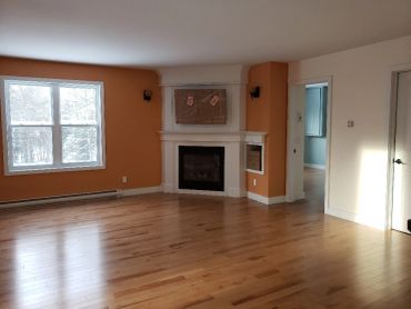 Salon vide avec parquet et cheminée.
