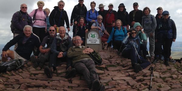 Group of hikers posing at the summit with a sign.