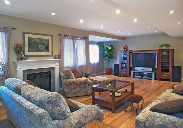 Living Room with grey Fireplace and brown ET unit with brown wood flooring and Fabric chesterfields