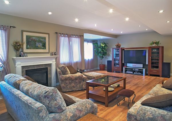 Living Room with grey Fireplace and brown ET unit with brown wood flooring and Fabric chesterfields