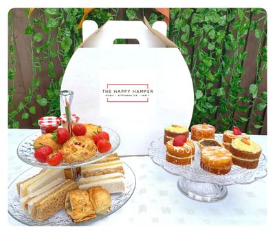 Afternoon tea hamper with sandwiches, sausage rolls, scones and cakes