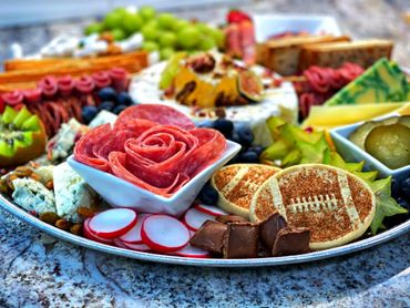 Charcuterie Board with an assortment of meat, cheese, and fruit with a sports theme board. 