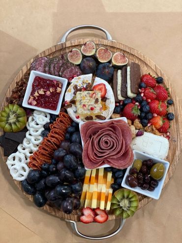 Charcuterie Board with an assortment of meat, cheese, and fruit with Brie wheel and honeycomb. 