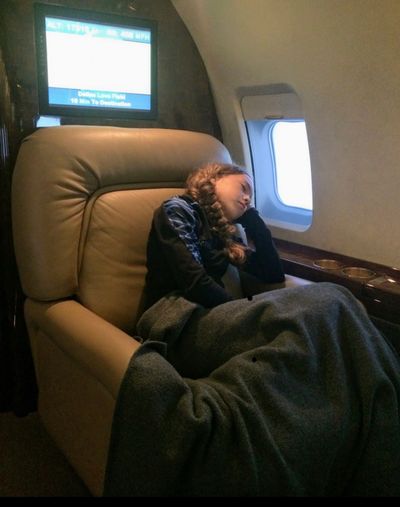 A woman curled up in a seat of an aircraft