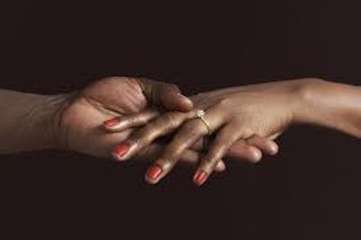 A person holding another person’s hand wearing a diamond ring