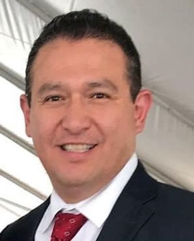 Smiling man in suit and red tie indoors.
