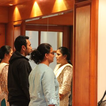 Three people standing and looking at a mirror in a room with wooden panels.
