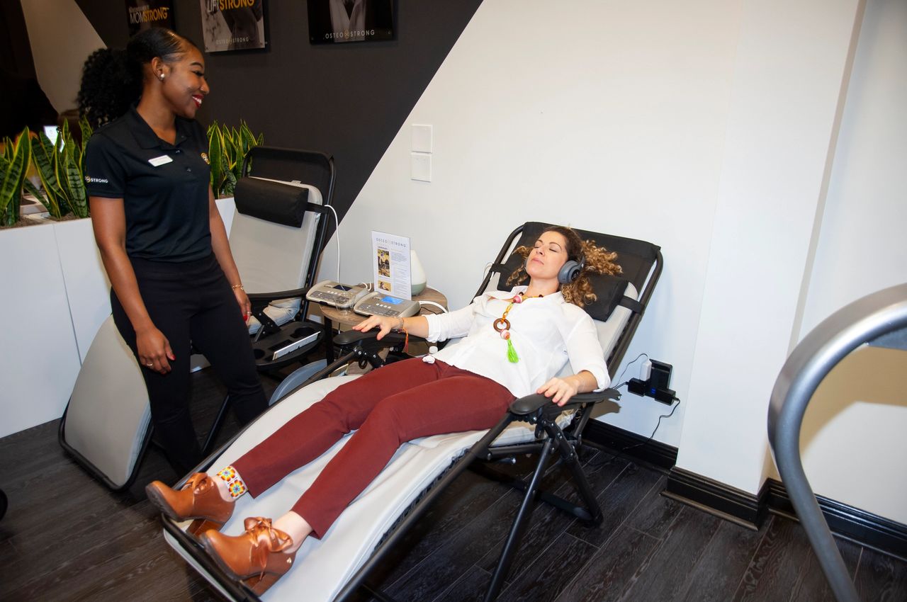 Woman relaxing on PEMF therapy mat for pain relief and healing at OsteoStrong Upper West Side NYC
