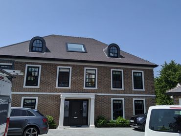 Two-story brick house with cars in front.
