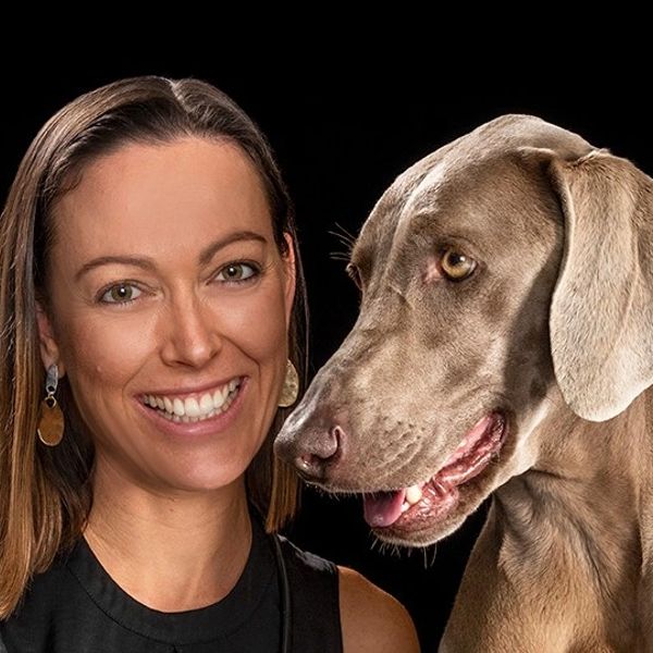 Smiling woman with her dog against a black background.