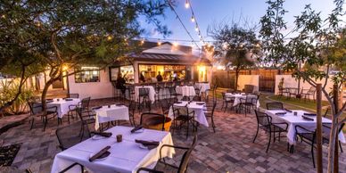 Outdoor restaurant patio with tables and string lights at dusk.