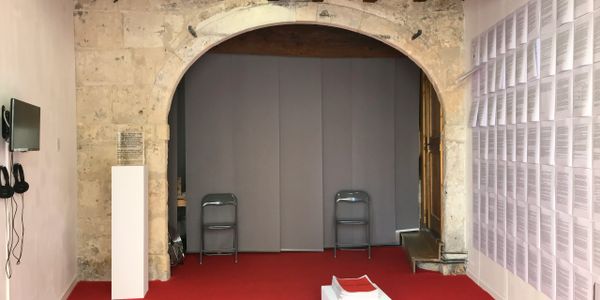 Art gallery room with stone arch, red carpet, and chairs.